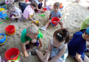 Przedszkolaki robią babki z piasku